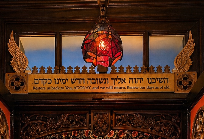 Above the ark of Kehillah Kedoshah Zikhron Zvi: the lamp, gilded wings, and the verse — Restore us back to You, and we will return; renew our days as of old