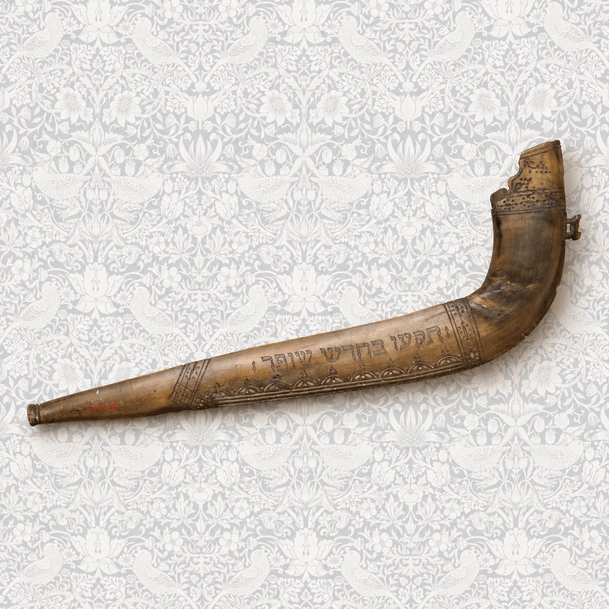 A carved ram's horn against William Morris pattern
